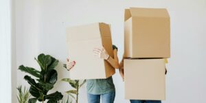 couple carrying cardboard boxes in living room